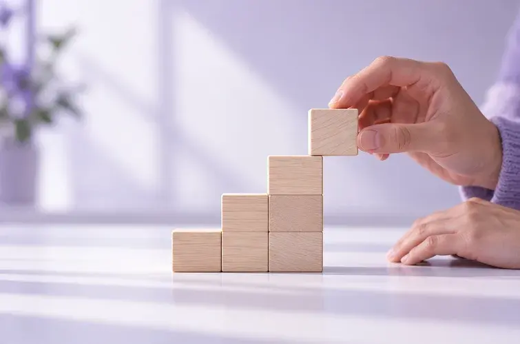 Des mains empilent des blocs de bois en forme d’escalier.