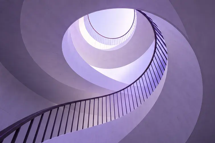 Un escalier en colimaçon baigné de lumière violette.